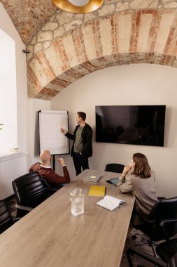 Şık bir ofiste yapılan bir iş toplantısında beyin fırtınası yapan ve işbirliği yapan katılımcılar