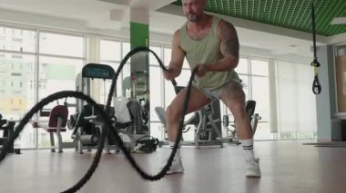 Modern ve iyi donanımlı bir spor salonunda güçlü bir idman yapan kaslı bir adam. Zindelik, güç ve kararlılık kavramı.