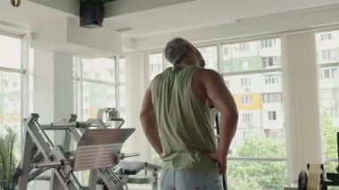 İyi donanımlı, modern bir spor salonunda ısınma egzersizleriyle güç eğitimine hazırlanan bir adam. Zindeliğe odaklanan motivasyonlu birey.