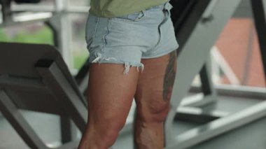 Spor salonunda spor sonrası bacaklarını esneten kot şort giyen bir sporcunun yakın çekimi..