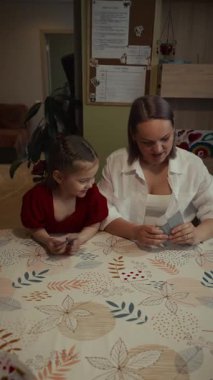 Mutlu aile evde kağıt oynuyor. Anne ve kızı birlikte iyi vakit geçiriyorlar..