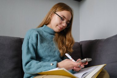 Araştırma amacıyla birden fazla iş yapan, okuyan ve akıllı telefonuyla meşgul olan genç bir kız..