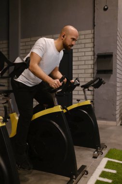 Sabit bisiklette bisiklet süren bir adam spor salonunda aktif fitness gösterileri yapıyor..