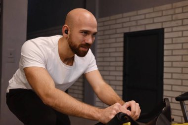 Kulaklıklar aracılığıyla müzik dinlerken evde sabit bisiklet kullanan bir birey..