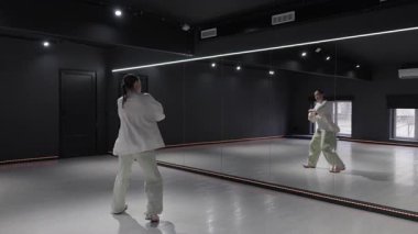 Genç bir kadın dans figürlerini ayna ve LED ışıkları olan bir stüdyoda çalışıyor..