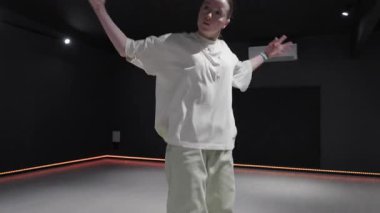 Karanlık bir stüdyoda renkli neon ışıklarıyla dans eden genç bir kadın..