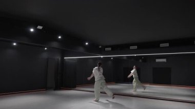 Genç bir kadın modern bir stüdyoda ayna ve neon ışıklarla dans ediyor..