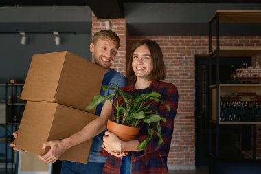 Yeni bir eve taşınmaktan zevk alan bir çift, kutular ve bir bitki taşıyorlar..