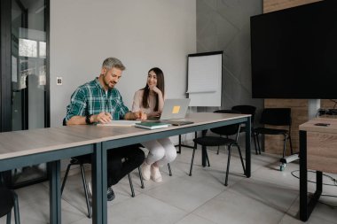 Açık ve parlak bir ofiste belgeleri inceleyen ve projeleri tartışan iki profesyonel