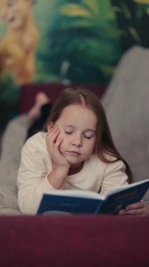 Genç bir kız kanepeye uzanmış, kendini kitabına kaptırmış. Bulanık arka plan rahat ve rahat bir atmosfer izlenimi veriyor. Sessizce okumak için mükemmel..