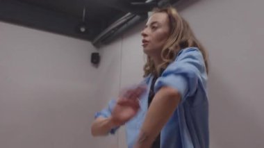 Genç bir kadın, parlak ve temiz bir stüdyoda anlamlı ve akıcı hareketlerle modern dans ediyor..