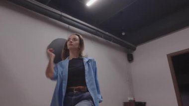 Enerjik kadın dans hareketleri sergiliyor. Kapalı alanda özgürlük ve kişisel neşeyi somutlaştırıyor..