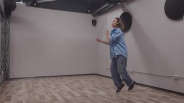 Enerjik kadın dansçı modern bir stüdyoda etkileyici hareketlerle dinamik ve çağdaş bir gösteri sergiliyor..