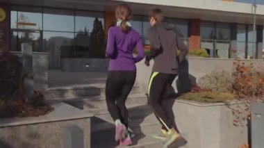A man and woman ascend outdoor stairs, engaged in a dynamic workout for improved fitness and health.