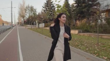 Şık siyah paltolu zarif genç bayan sonbahar boyunca kentin kaldırımlarında güvenle yürür..