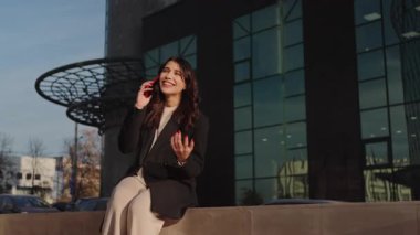 Gülümseyen genç bir kadın canlandırmalı bir telefon görüşmesinde, şehir ortamında neşe ve bağlantısını ifade ediyor..