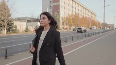 Şehrin kaldırımında amaçsızca yürüyen özgür genç bir kadın, bir dizüstü bilgisayarla güne hazır..