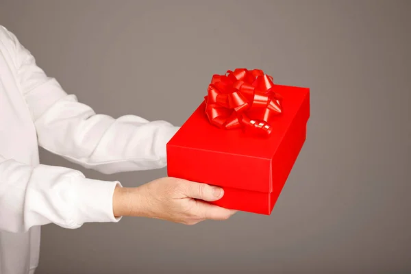 Female Hands Holding Red Gift Box Red Ribbon Grey Background Стокова Картинка