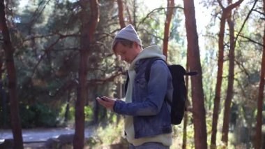 Portrait of a mobile phone in the hands of a male traveler walking through the forest. Social networks Navigator and messenger. Use your mobile phone for a walk in the woods