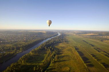 Balon gün doğumunda nehrin üzerinden uçar.