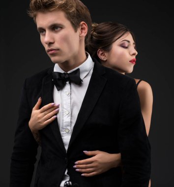 Siyah arka plan üzerine izole atış siut ve papyon ile kız arkadaşı onu kucaklayan seksi beyefendi kırpılmış