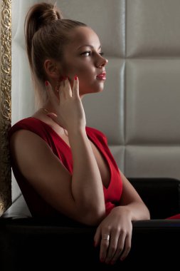 Kulüpte kanepede oturan genç bir kadının portresi.