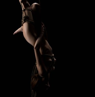 Çıplak güzel sarışın siyah arka plan üzerinde baş aşağı izole atış asılı bir ip ile bağladı