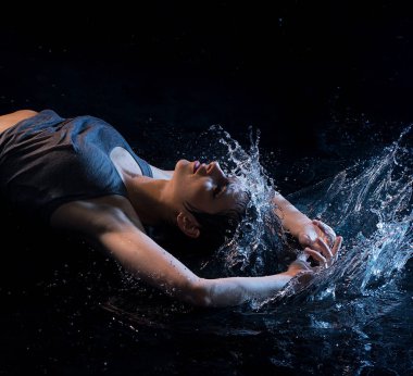 Seksi kız üst ve su sıçramalarına tarafından çevrili karanlık odada yatan dizeleri giyiyor