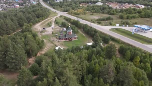キロフ地方の小さなポドシノヴェツの町の森に囲まれた教会の新しい建物のドローン空中ビュー — ストック動画