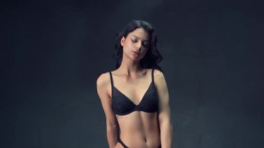 BDSM için kırmızı kadife bankta siyah külotlu üstsüz esmer kadın.