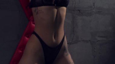 Siyah iç çamaşırlı baştan çıkarıcı genç bir kadın elleri kelepçeli ve bdsm stüdyosunda şaplak atıyor.