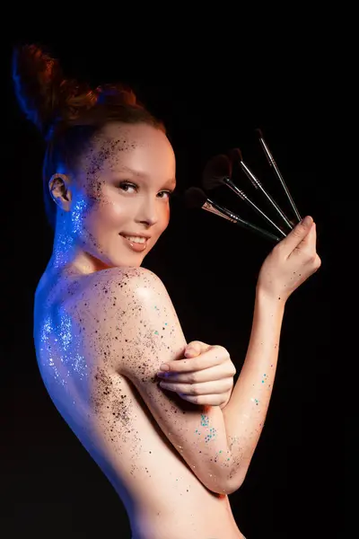 Sensual Topless Female Glitter Painted Body Standing Makeup Brushes Studio Стокова Картинка