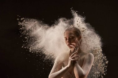 İç çamaşırlı, sakin genç bayan yüzlerine dokunuyor ve kara arka plandaki bulutların yanında gözlerini kapıyor.