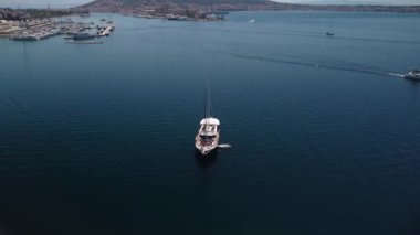 Hırvatistan 'da güneşli bir günde dalgalı deniz kıyısında yüzen beyaz teknenin hava manzarası