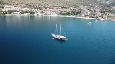 Hırvatistan 'da güneşli bir günde dalgalı deniz kıyısında yüzen beyaz teknenin hava manzarası