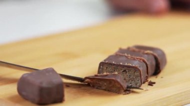 Hafif mutfaktaki kesme tahtasındaki ince dilimlere bıçakla çikolata kesme hareketi.