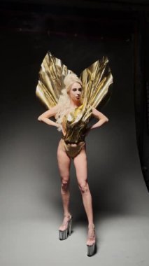 Stüdyoda kamerada poz verirken yüksek topuklu ayakkabılar giyen şehvetli genç bir kadının yan görüntüsü.