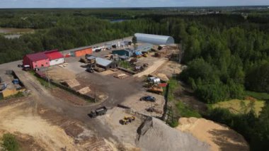 Rusya 'nın Kirov Oblastı, Kirs' ta yaz günü verimli ormanlık, göl ve gölet yakınlarındaki endüstriyel kereste fabrikasının yüksek açılı insansız hava aracı görüntüsü.