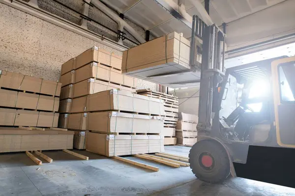 Modern forklift makinesi fabrikada çalışırken ahşap paneller ile depoda hareket ediyor.