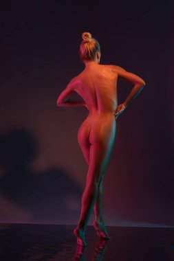 Sarışın, belinde kolları olan, koyu mor arka planda zarif dans eden genç ve seksi bir kadının arka planı.