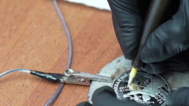 Bu video elektroliz sürecini kullanarak gümüş paranın nasıl temizleneceğini gösteriyor. Videoda madeni para bir solüsyonla temizleniyor ve madeni paraya elektrik akımı uygulanıyor..