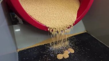 Bozuk para temizleme işlemi - kırmızı zıpzıp sarı granülleri siyah paspasa döküyor.
