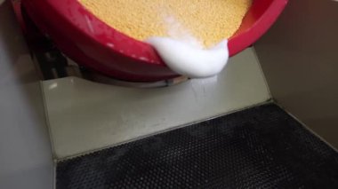 Bu video, sarı kumu karıştıran dönen bir davul çalar makinesini gösteriyor. Makine fabrikada ya da endüstriyel ortamda. Davul dönüyor ve kum karışıyor..