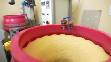 Bu video, bir fabrikadaki metal parçalarının kumlama işlemini gösteriyor. Video, kum püskürtme makinesinin yakın çekimini ve parçaları yükleme ve boşaltma sürecini gösterir..