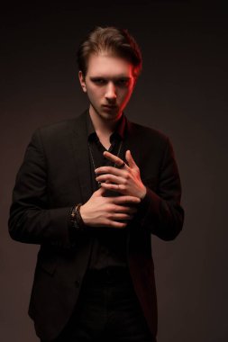 Zarif takım elbiseli ciddi bir genç adam çenesine dokunuyor ve kameraya bakıyor. Şeytani bir kavram.