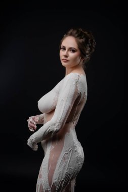 Bir model zarif bir şekilde loş bir stüdyoda poz verir. Karmaşık vücut boyalarıyla süslenir, sanatını ve zarafetini sergiler..