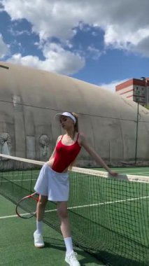 Genç bir sporcu güneşli havanın tadını çıkarırken tenis yeteneklerini açık havada sergiliyor..