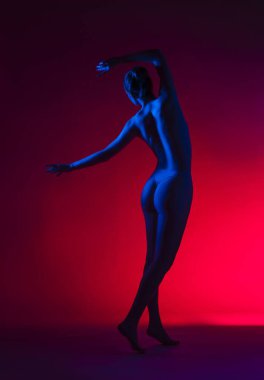 Stüdyoda kırmızı ve mavi neon ışıkları olan genç bir kadının yan görüntüsü.