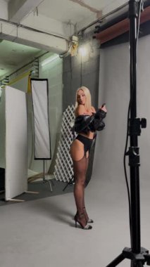 Bir kadın, moda iç çamaşırlarıyla, bir stüdyoda moda fotoğraflarının arasında rahatça poz veriyor..