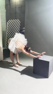 Bale kostümü giymiş bir kadın dans stüdyosunda zarif bir şekilde esniyor ve bir gösteriye hazırlanıyor..